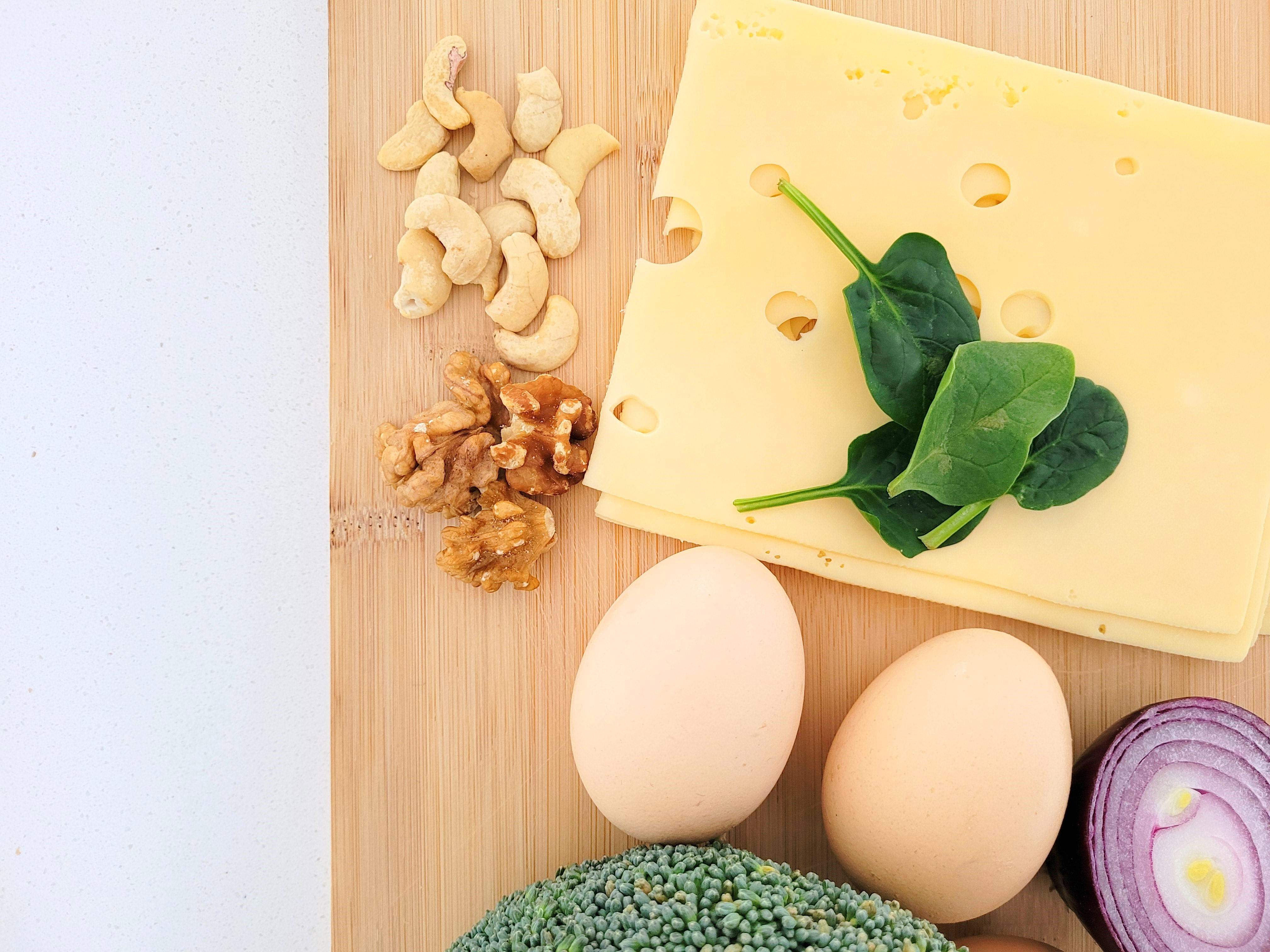 Zdjęcie na którym widać produkty żywnościowe, jajka, cebulę, szpinak, ser i orzechy