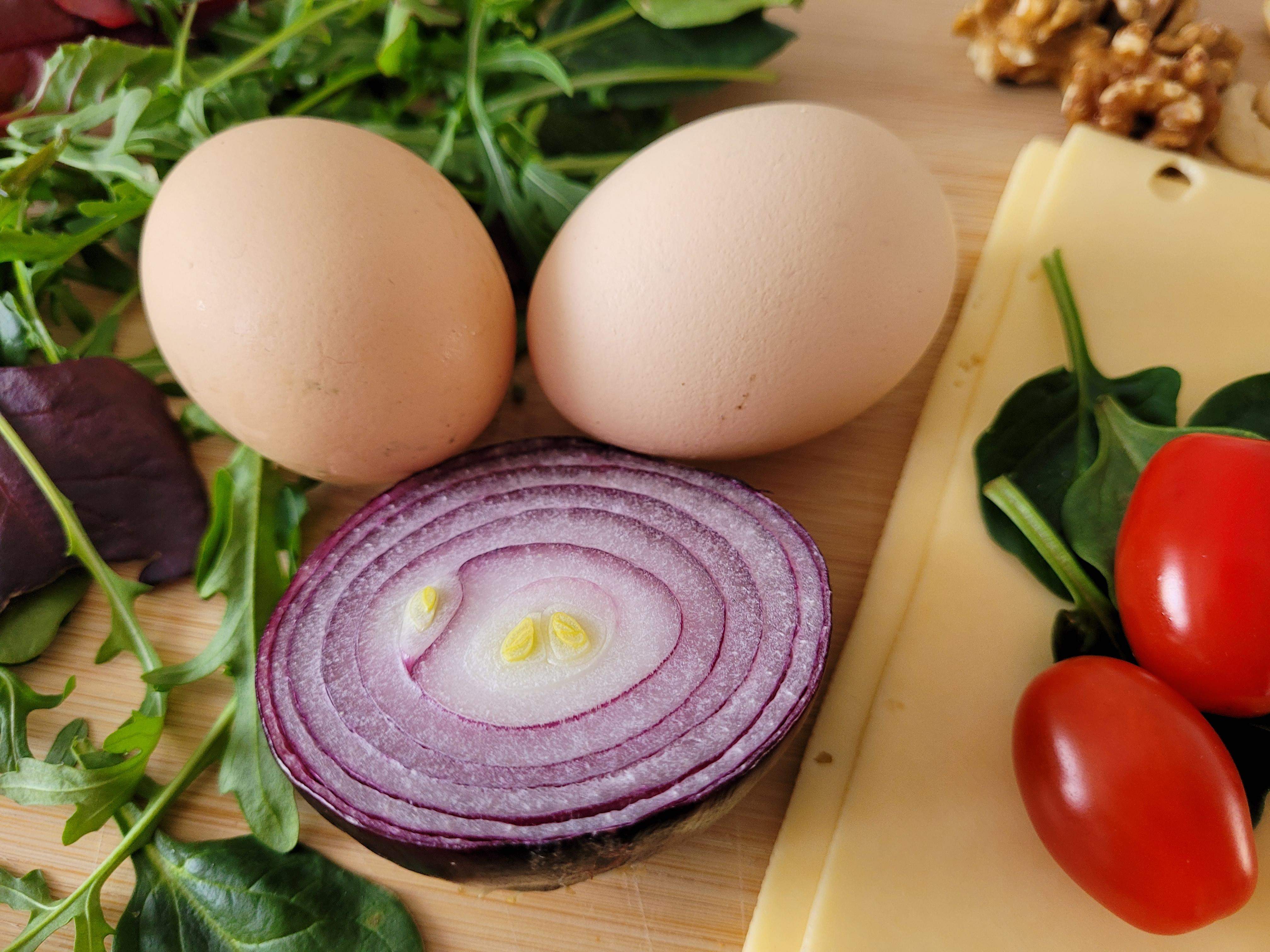 Zdjęcie na którym widać produkty żywnościowe, cebulę, jajka, pomidory koktajlowe, ser